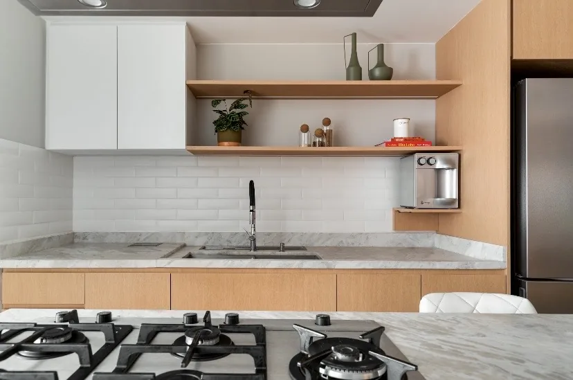 Cozinha com prateleiras abertas em madeira clara e bancada em mármore branco